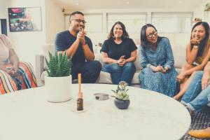 A group of people sitting on couches around a coffee table talking and laughing